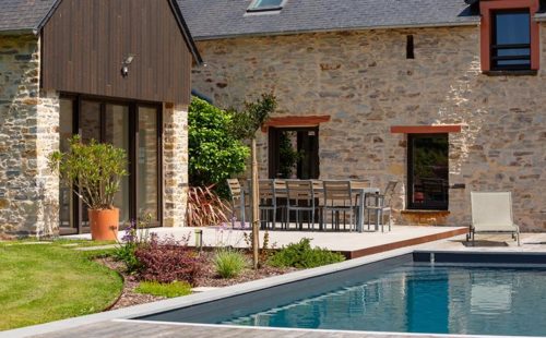 vue d’une piscine en béton avec une maison en pierre