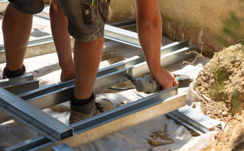 un poseur en train d'installer une ossature métallique pour une terrasse extérieure